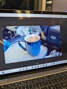 an open laptop computer sitting on top of a table next to a cup of coffee