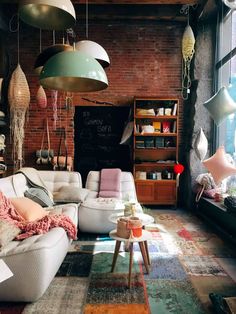 a living room filled with lots of furniture next to a brick wall covered in hanging lights