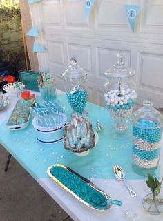 a table topped with lots of blue and white desserts next to a garage door