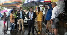 a group of people standing under umbrellas on a rainy day in the rain with one man holding an umbrella