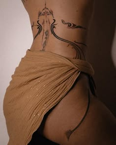 a woman with a tattoo on her lower back is wearing a brown wrap around her waist