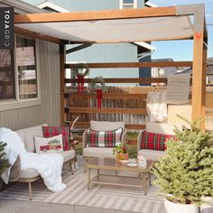 a covered patio with couches, chairs and christmas decorations on the back porch area