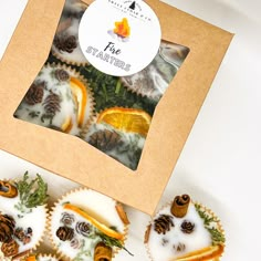 four decorated cupcakes in a box with pine cones on top and frosting