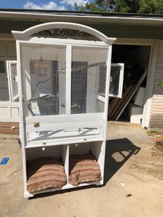 a white bird cage sitting on top of a wooden shelf