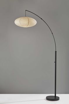 a black floor lamp with a white shade on it's head and an oval light fixture