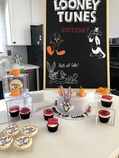 a birthday cake and cupcakes on a kitchen counter with a sign in the background