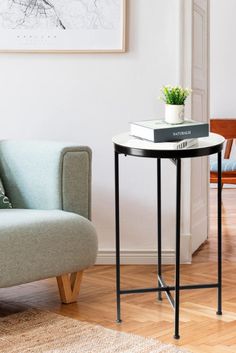 a living room with a couch, table and chair next to a painting on the wall