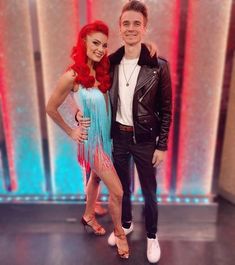 a man standing next to a woman on top of a dance floor in front of a red and blue background