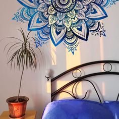 a bed with a blue comforter next to a potted plant