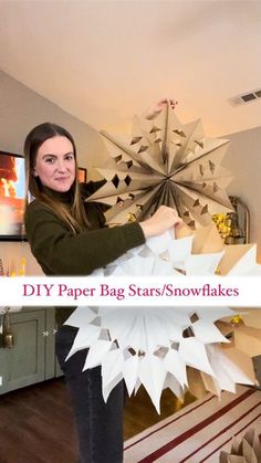 a woman standing in front of a large paper snowflakes with the words diy paper bag stars / snowflakes