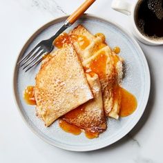 pancakes with syrup on a plate next to a cup of coffee