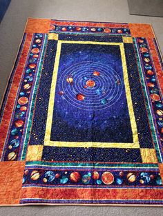 a quilted table runner with an image of the solar system in blue and orange