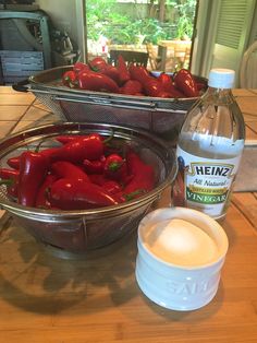 some red peppers are sitting on a table next to a bottle of water and a bowl of salt