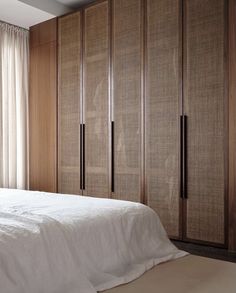 a bed with white sheets and pillows next to wooden closets in a bedroom area