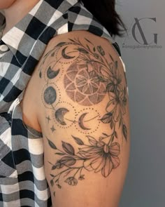 a woman's arm with a tattoo on it that has flowers, leaves and moon phases