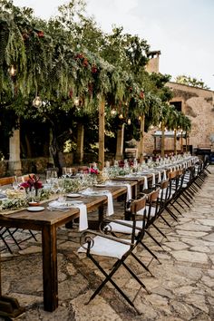 a long table is set up with place settings for an outdoor wedding reception in the countryside