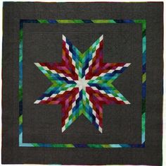 a quilted wall hanging with a star design on the front and center, in multi - colored strips