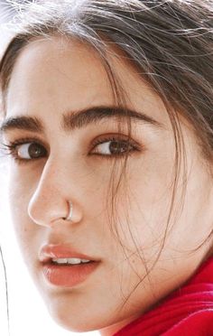 a close up of a person wearing a red scarf and looking at the camera with a serious look on her face