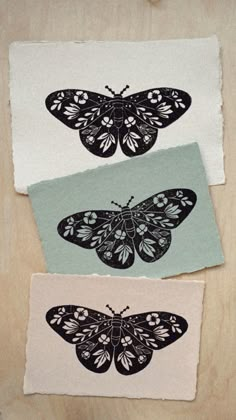 three butterflies are shown on top of two pieces of paper that have been cut out