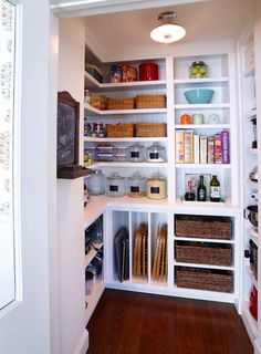 an organized pantry with white shelving and wooden floors