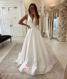 a woman is taking a selfie in her wedding dress while looking at her cell phone