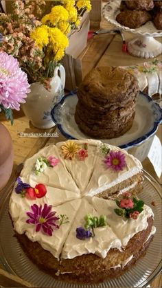 there is a cake with white frosting and flowers on the plate next to it