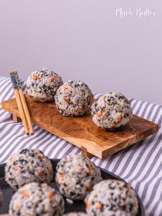 several balls of food on a wooden board with chopsticks next to it and another plate full of them