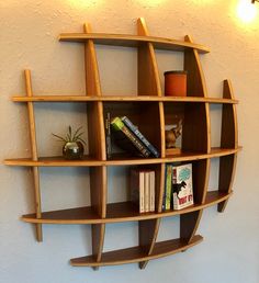 a wooden shelf with books on it against the wall next to a plant and lamp