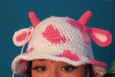 a woman wearing a pink and white knitted hat with hearts on the side,