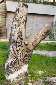 a tree trunk with an intricate design on it's side in front of a brick building