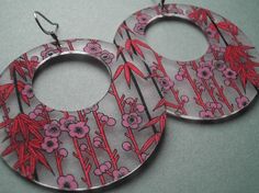 the earrings are decorated with pink flowers and red bamboo sticks on it's sides