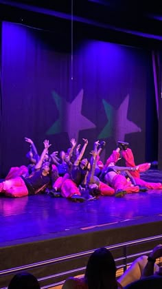 some people are laying on the floor in front of a stage with purple lights and stars