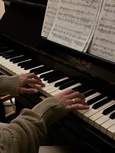 a person playing the piano with sheet music on it's back and hands in front