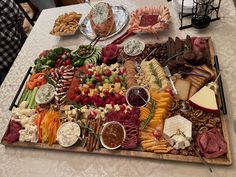 a platter filled with lots of different types of cheeses, meats and fruit