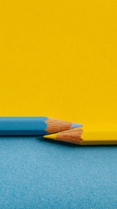 a blue and yellow pencil sitting next to each other on top of a blue surface