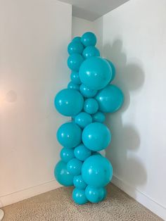 a tall balloon column in the corner of a room with white walls and carpeted flooring