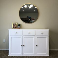 a white dresser with a round mirror above it