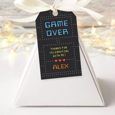 a game over tag on top of a white pyramid shaped object with a ribbon tied around it