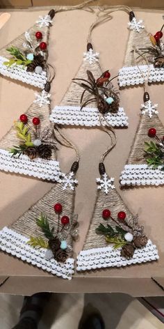 christmas tree ornaments made out of yarn and pine cones are displayed on a cardboard box