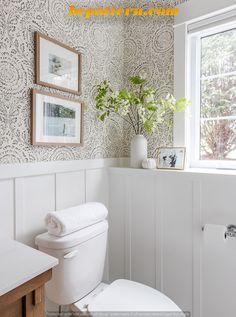 a white toilet sitting in a bathroom next to a window with pictures on the wall