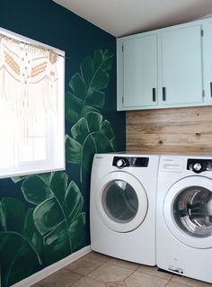 a washer and dryer in a room with green leaves painted on the wall