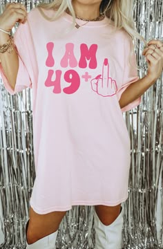 a woman wearing a pink shirt with the words i am 19 and a peace sign on it