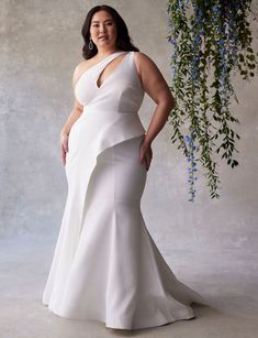 a woman in a white dress standing next to a plant