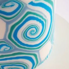 a close up view of a blue and green swirl pattern on a coffee cup with white background