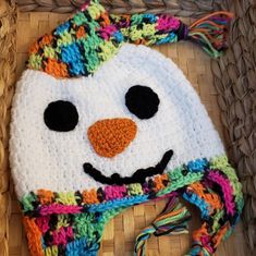 a crocheted hat with a smiling snowman face on it's side