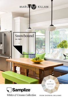 a kitchen with white cabinets and green benches in front of a window that reads snowbound