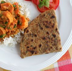 a white plate topped with rice and meat next to a slice of tomato on top of it