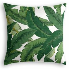 a green and white pillow with large leaves on the front, sitting against a white background