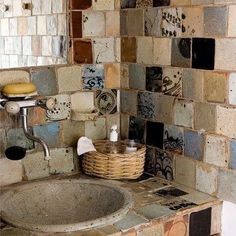 a bathroom sink sitting under a mirror next to a wall covered in tile tiles with different designs on it