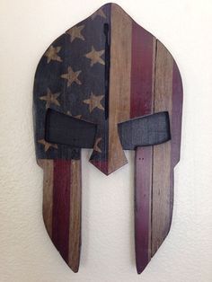 a wooden wall hanging with an american flag and spartan helmet on it's side